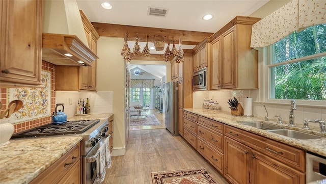 kitchen with light stone counters, a sink, visible vents, appliances with stainless steel finishes, and custom exhaust hood