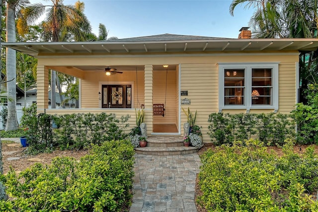 view of front of home featuring covered porch, a chimney, and ceiling fan