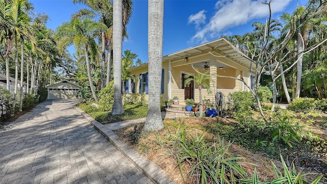 view of front of house featuring an outbuilding, ceiling fan, covered porch, and a garage