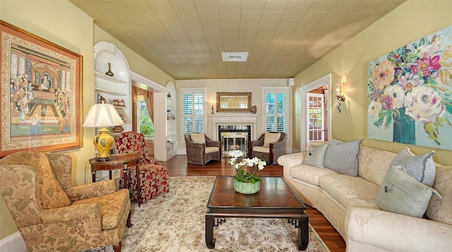 living room with visible vents, a glass covered fireplace, and wood finished floors