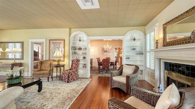 living room with visible vents, baseboards, a chandelier, a fireplace, and wood finished floors