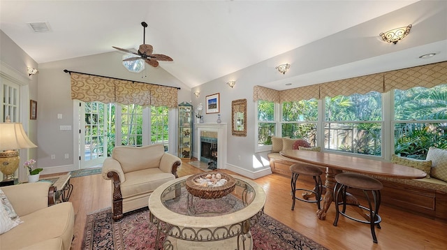 living room with visible vents, a lit fireplace, a ceiling fan, and wood finished floors