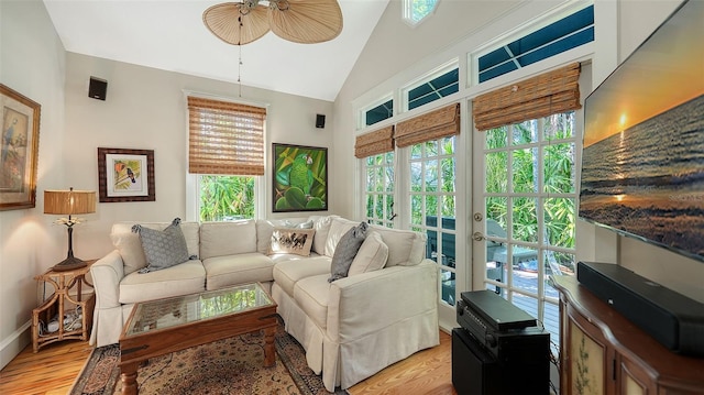 living area with high vaulted ceiling, light wood-type flooring, and a ceiling fan