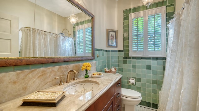 bathroom with vanity, toilet, curtained shower, a chandelier, and tile walls
