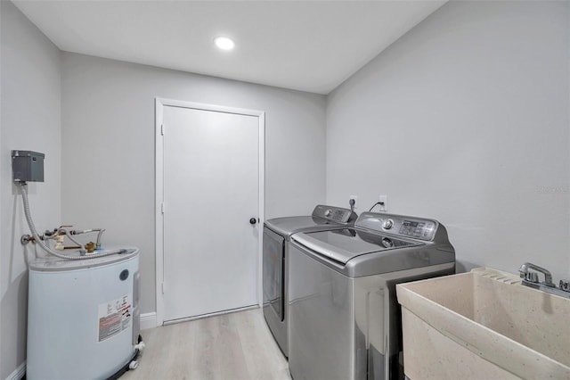 laundry room featuring light wood-type flooring, water heater, sink, and washer and clothes dryer