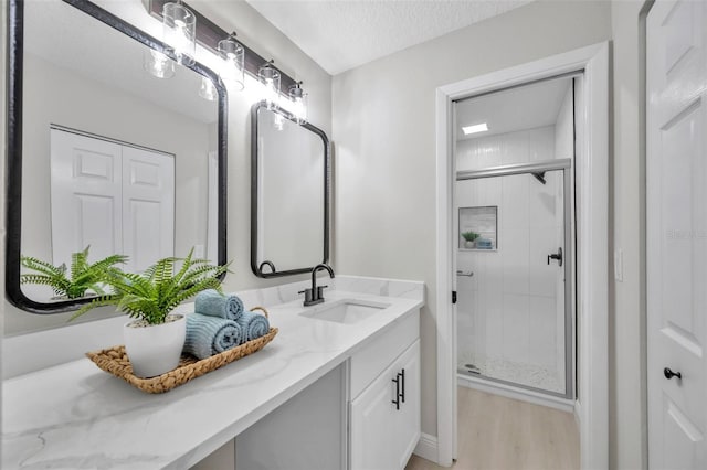 bathroom with hardwood / wood-style flooring, vanity, a shower with shower door, and a textured ceiling