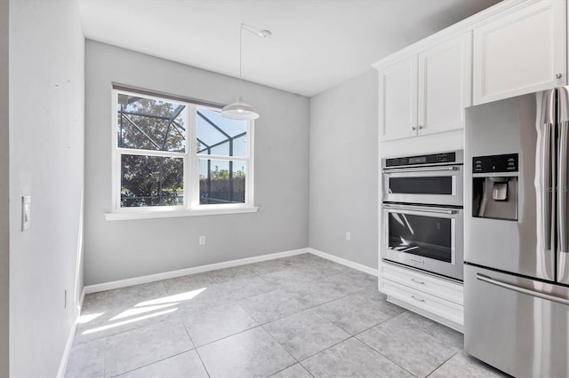 kitchen with light tile patterned floors, stainless steel appliances, white cabinetry, baseboards, and decorative light fixtures