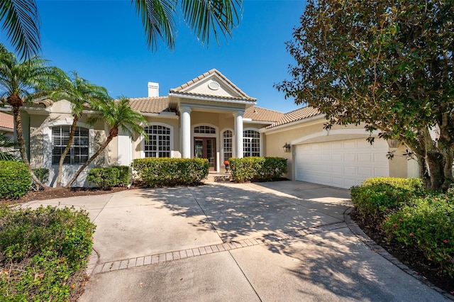 view of front of home featuring a garage, a chimney, concrete driveway, and a tiled roof