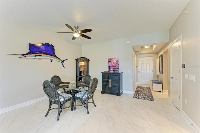 interior space featuring a ceiling fan, marble finish floor, and baseboards