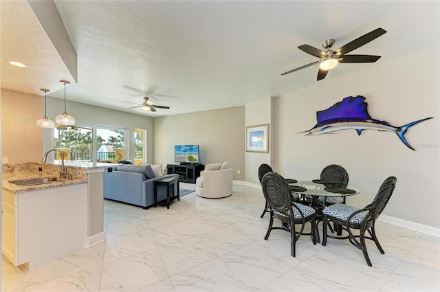 dining space with a textured ceiling, marble finish floor, ceiling fan, and baseboards