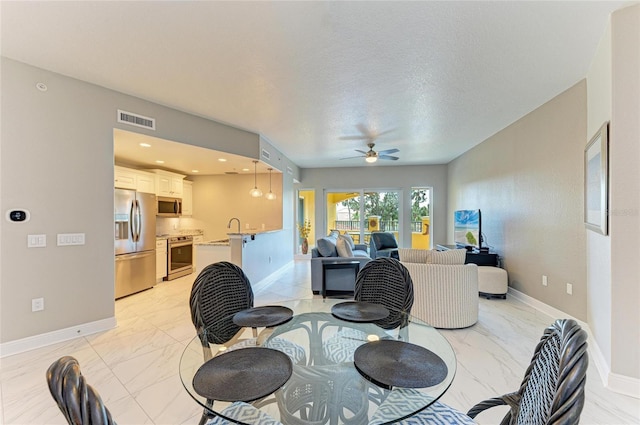 dining room with marble finish floor, visible vents, a textured ceiling, and baseboards