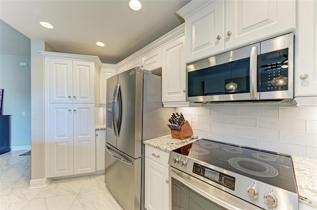 kitchen with marble finish floor, appliances with stainless steel finishes, white cabinets, and decorative backsplash