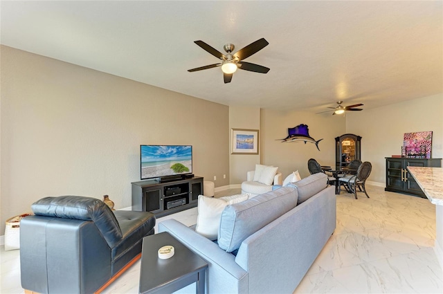 living area featuring marble finish floor, a ceiling fan, and baseboards