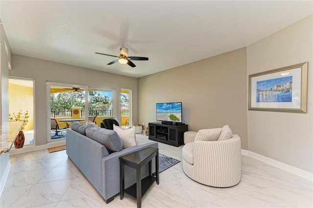 living area featuring a ceiling fan, marble finish floor, a textured ceiling, and baseboards