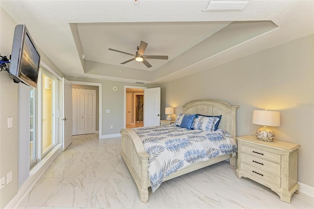 bedroom featuring visible vents, baseboards, a raised ceiling, ceiling fan, and marble finish floor