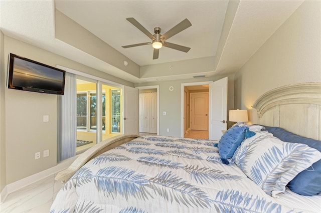 bedroom featuring access to exterior, a tray ceiling, visible vents, a ceiling fan, and baseboards