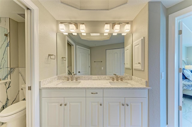 ensuite bathroom featuring a sink, double vanity, toilet, and connected bathroom