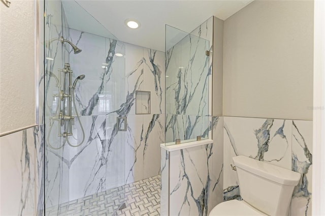 bathroom with a marble finish shower and toilet