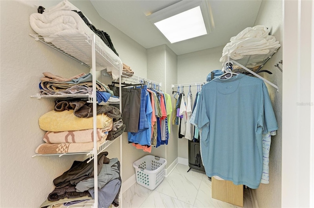 walk in closet with marble finish floor and a skylight