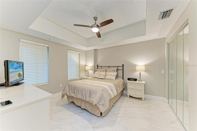 bedroom with marble finish floor, a raised ceiling, visible vents, ceiling fan, and baseboards