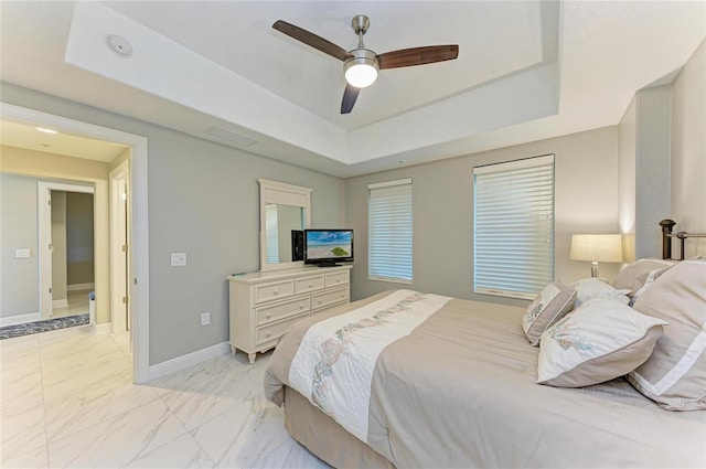 bedroom featuring marble finish floor, a raised ceiling, a ceiling fan, and baseboards