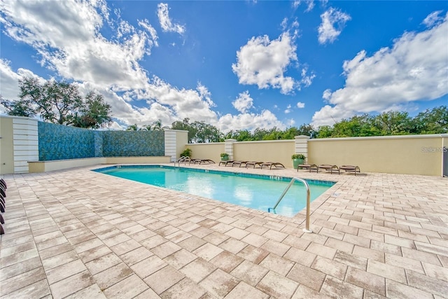 pool with a patio and fence