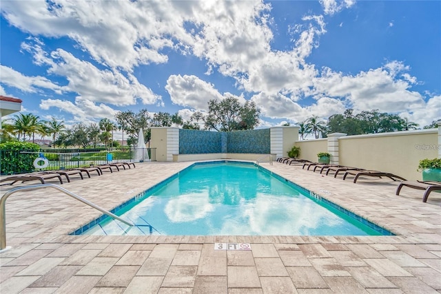 community pool with fence and a patio