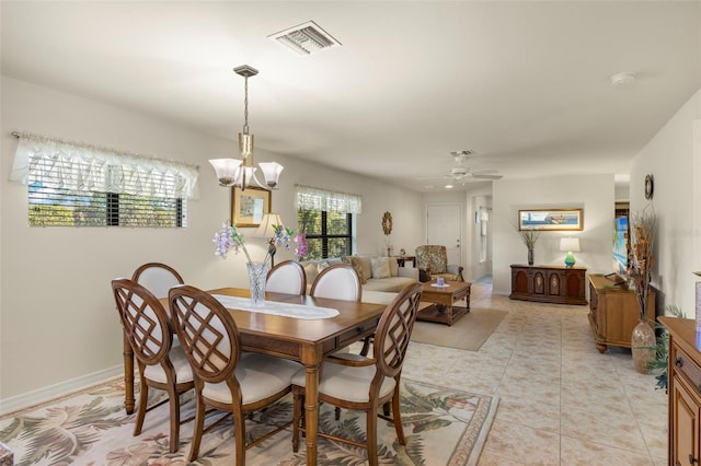 tiled dining area with ceiling fan with notable chandelier