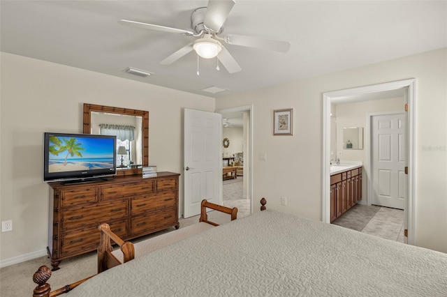 bedroom with ceiling fan, ensuite bath, and light carpet