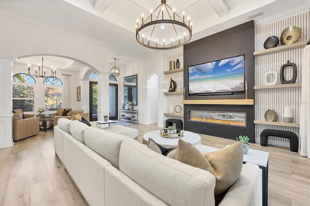 living area with light wood-type flooring, a glass covered fireplace, and a chandelier