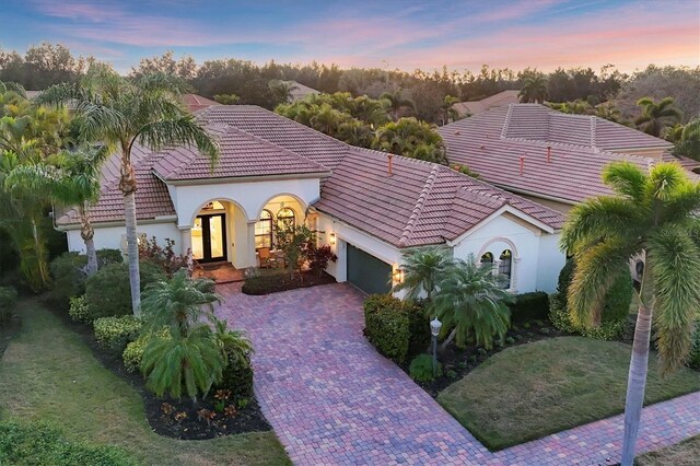 7024 Brier Creek Ct, Lakewood Ranch, FL 34202 - mediterranean / spanish house featuring a garage, french doors, decorative driveway, and a tiled roof