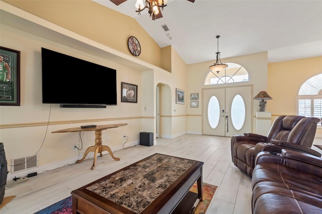 living area with light wood finished floors, visible vents, arched walkways, and vaulted ceiling