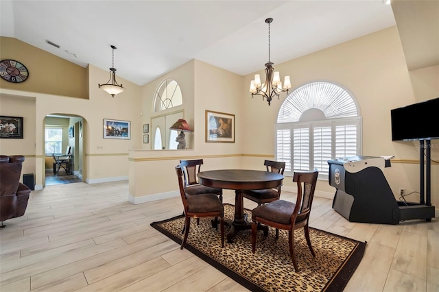 dining room featuring light wood-style floors, visible vents, arched walkways, and a notable chandelier