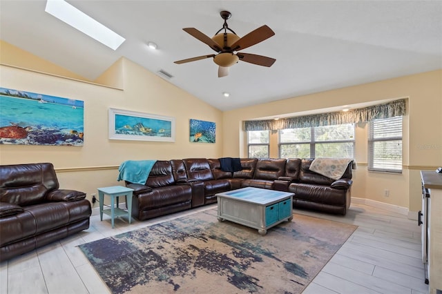 living area featuring ceiling fan, visible vents, baseboards, light wood-type flooring, and lofted ceiling with skylight