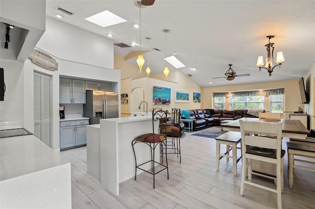 kitchen featuring visible vents, stainless steel fridge with ice dispenser, open floor plan, hanging light fixtures, and light countertops