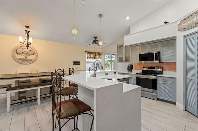 kitchen featuring stainless steel appliances, light countertops, glass insert cabinets, and hanging light fixtures