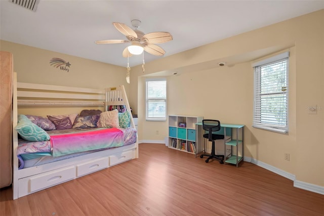 bedroom featuring ceiling fan, wood finished floors, visible vents, and baseboards