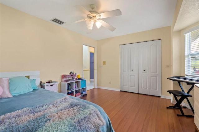 bedroom with baseboards, a closet, visible vents, and wood finished floors