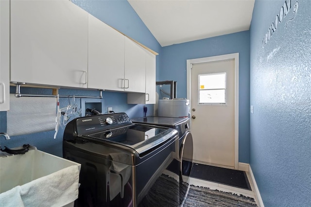 washroom featuring a sink, baseboards, water heater, cabinet space, and washer and clothes dryer