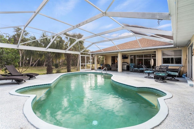 outdoor pool with glass enclosure and a patio