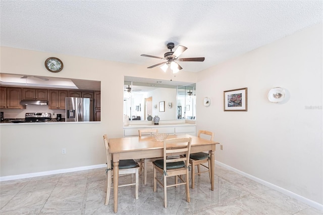 dining area featuring a ceiling fan, a textured ceiling, and baseboards