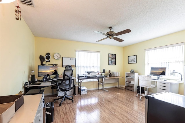 office area featuring light wood-style floors, a wealth of natural light, visible vents, and a ceiling fan