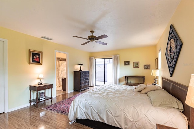 bedroom with access to exterior, visible vents, baseboards, and wood finished floors