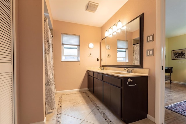 bathroom with double vanity, a closet, a sink, baseboards, and tile patterned floors