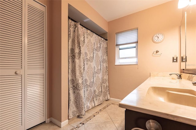 full bathroom with double vanity, a closet, a sink, baseboards, and tile patterned floors