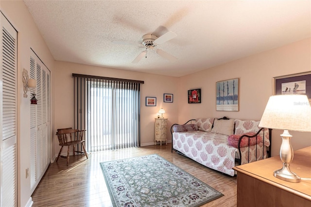 bedroom with baseboards, a textured ceiling, a ceiling fan, and wood finished floors