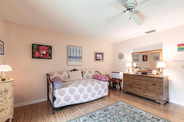 bedroom with light wood-style flooring, visible vents, ceiling fan, and baseboards