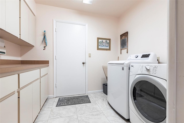 clothes washing area with cabinet space, baseboards, marble finish floor, and washing machine and clothes dryer