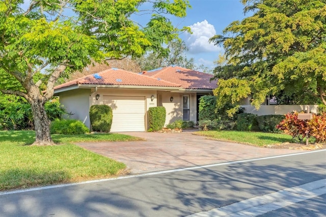 view of front facade with a tiled roof, an attached garage, decorative driveway, a front lawn, and stucco siding