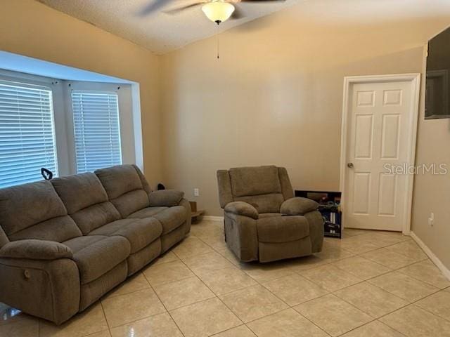 living room with light tile patterned floors, ceiling fan, baseboards, and vaulted ceiling